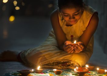 A Little girl making Rangoli and decorating with Oil lamps for Diwali celebration in India.