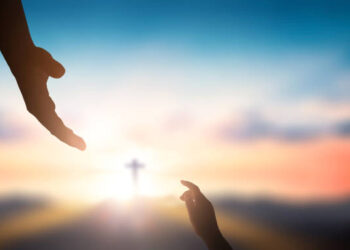 Help hand of God reaching over blurred cross on sunrise  background